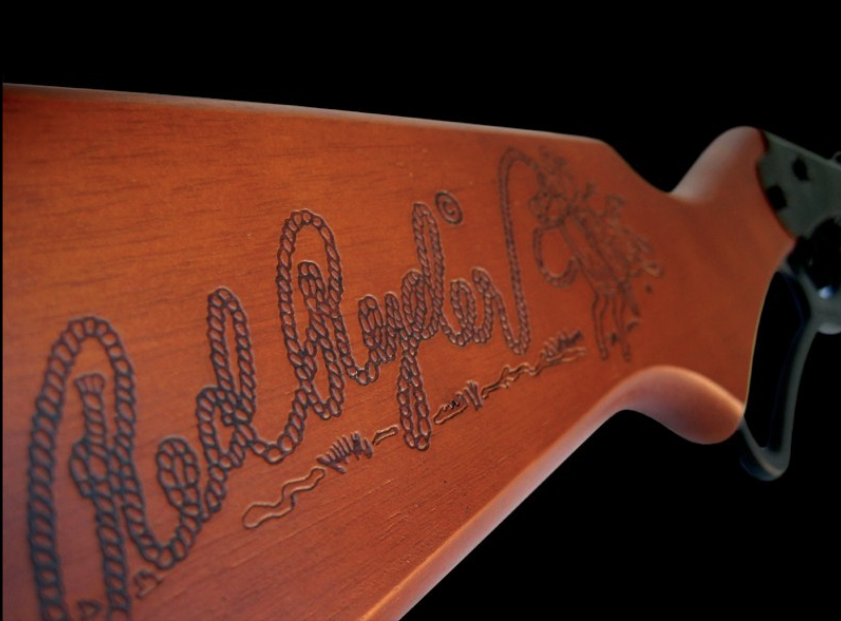 A closeup of the Red Ryder BB Gun stock with carved Red Ryder logo in rope with a cowboy lasso