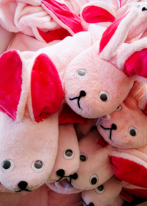 A pile of pink bunny pajama slippers in the shape of a bunny with ears and eyes makes for the most authentic bunny suit ever.
